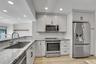Well-appointed kitchen featuring light-toned cabinetry, stainless steel appliances, a subway tile backsplash, recessed lighting, and wood-finish floor
