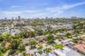 Aerial perspective showcasing a residential property amidst a developed urban area with distant high-rise buildings