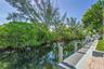 Waterfront property featuring a private boat dock, lush mature trees, and a paver patio