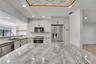 Kitchen featuring light gray cabinetry, stainless steel appliances, a tile backsplash, and stone countertops