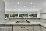Kitchen featuring white shaker cabinetry, stainless steel sink, gold-finish faucet, and light-toned stone countertops