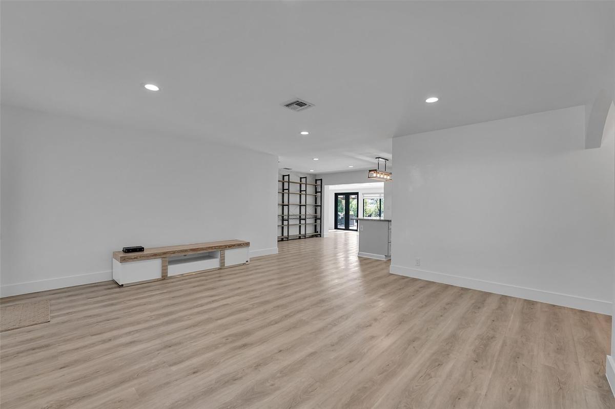 Recessed lighting, light wood-finish flooring, white walls, and a built-in media console
