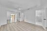 Wood-finish flooring, white walls, mirrored closet doors, ceiling fan with integrated lighting, and a glass-enclosed shower with tile surround
