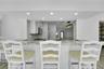 Kitchen featuring a breakfast bar with stone-finish countertop, recessed lighting, white cabinetry, stainless steel appliances, and a subway tile back
