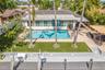 Outdoor pool with integrated steps, artificial turf lawn, and extensive paved patio area