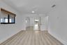 Wood-finish flooring, mirrored closet doors, a contemporary ceiling fan, and a single window with blinds