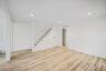 Open-concept interior featuring wood-finish flooring, recessed lighting, and a staircase with white balusters and a decorative post
