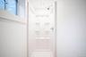First floor shower enclosure featuring a high-gloss composite surround with integrated storage shelving, a wall-mounted showerhead, and a recessed cei