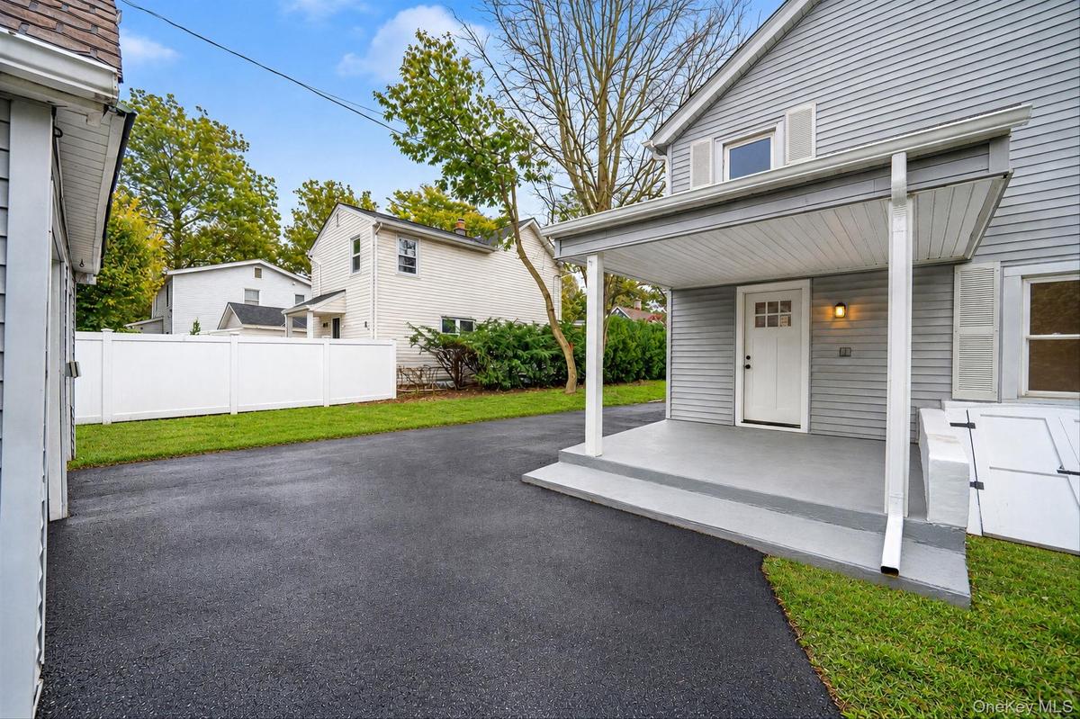 Exterior featuring horizontal siding, a covered porch with concrete flooring, an asphalt driveway, and a white privacy fence