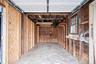 Enclosed garage featuring a concrete floor, exposed timber stud walls, integrated wooden shelving, and a multi-pane window