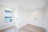 Neutral-toned interior space featuring vinyl wood-finish flooring, recessed lighting, white six-panel doors, and a double-hung window with wide casing