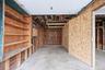Garage space featuring exposed timber framing, concrete flooring, built-in wooden shelving units, and overhead storage rafters