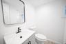First floor bathroom featuring a grey vanity cabinet with a white countertop, oval basin, matte black faucet, and a rectangular mirror with a rounded 