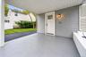 Covered carport featuring gray siding, a painted concrete floor, a six-pane window exterior door, and a wall-mounted light fixture