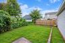 Private backyard featuring a fenced perimeter, brick-edged garden beds, and mature landscaping *virtually edited
