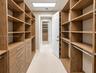 Custom walk-in closet featuring floor-to-ceiling wood-finish cabinetry, built-in shelving, integrated storage drawers, and recessed overhead lighting