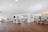 Open-concept interior featuring wood-finish flooring, recessed lighting, a built-in mirrored wall, and a kitchen equipped with wood-finish cabinetry a
