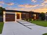 Modern exterior featuring a combination of stucco and wood-finish cladding, single-car garage, integrated screen paneling, and concrete slab walkway w