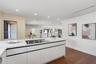 Kitchen island featuring white flat-panel cabinetry, a solid surface countertop, and an integrated cooktop, complemented by recessed lighting and wood
