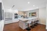 Kitchen featuring flat-panel cabinetry, a central island with a solid surface countertop, wood-finish flooring, integrated wall ovens, and a stone-sty