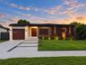Single-story residence featuring a mid-century modern aesthetic, wood-paneled exterior accents, a concrete driveway with stone drainage detail, a step