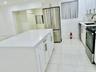Kitchen featuring white cabinetry, an island with a solid surface countertop, stainless steel appliances, and large-format tile flooring throughout