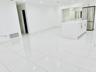 Large-format white tile flooring, central kitchen island with countertop, and stainless steel refrigerator