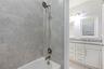 Shower area featuring stone-look wall tile and a multi-setting handheld showerhead