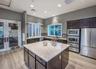Kitchen featuring a central island with a stone countertop, dark wood cabinetry, stainless steel built-in appliances, recessed lighting, and wood-fini