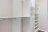 Custom closet featuring floor-to-ceiling white cabinetry, built-in shelving, integrated hanging rods, and a bank of storage drawers with brushed metal