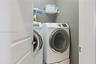 Laundry area featuring a side-by-side washer and dryer set with pedestal bases and a mounted wire shelving unit