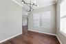 Interior space featuring wood-finish flooring, crown molding, a modern multi-arm sputnik chandelier, and horizontal window blinds
