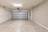 Two-car garage featuring a concrete floor, finished walls, overhead lighting, and an automated door opener