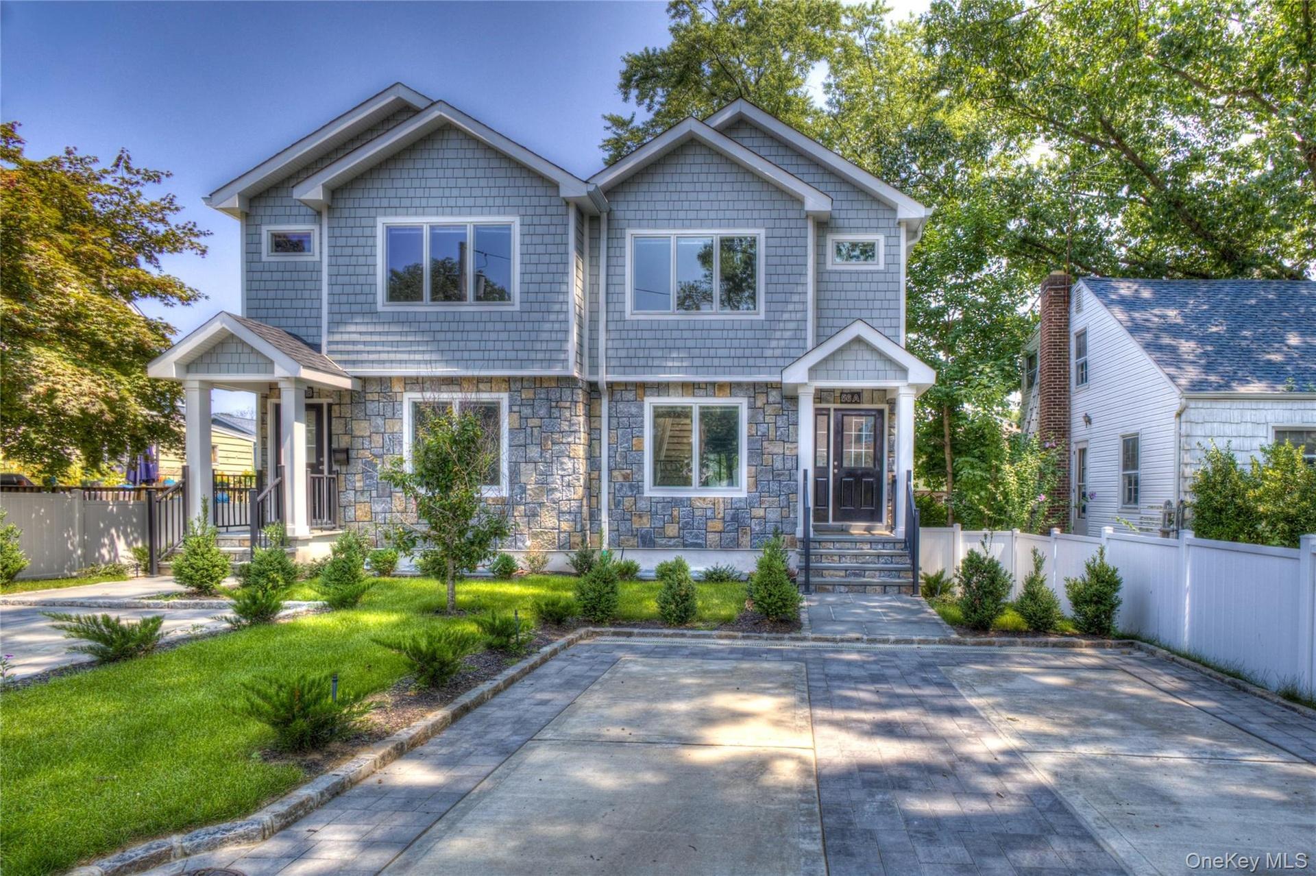 Two-story exterior featuring stone veneer siding, shingle-style upper cladding, dual covered entryways, and a paved driveway