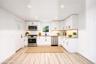 Kitchen featuring white Shaker-style cabinetry, stainless steel appliances, light-toned stone-finish countertops, subway tile backsplash, and vinyl wo