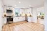 Kitchen featuring white shaker-style cabinetry, stainless steel appliances, a light-toned stone-finish countertop, subway tile backsplash, and vinyl w