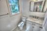 Vanity featuring a stone-patterned countertop, integrated basin with metal hardware, white cabinetry, rectangular wall mirror, and large-format tile f