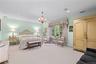 Spacious room featuring patterned wall-to-wall carpeting, crown molding, recessed lighting, and a multi-tiered decorative chandelier