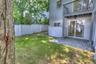 Rear exterior featuring a paver patio, elevated wood balcony, white vinyl privacy fencing, and sliding glass doors
