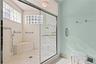 Walk-in shower featuring natural stone tiling, a built-in bench seat, glass block windows, and a semi-frameless glass enclosure