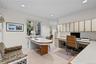 Built-in desk with integrated workspace, custom wall-mounted cabinetry, recessed lighting, and large windows with exterior surroundings. This room cou