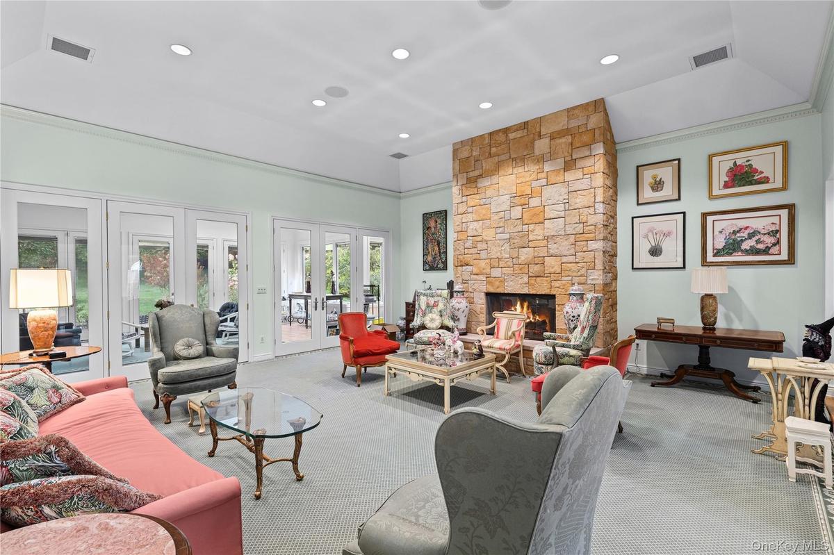 Vaulted ceiling with recessed lighting, stone fireplace, and multiple sets of glass-paned double doors