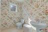 Master Bath featuring floral-patterned wallpaper, pedestal sink with polished chrome hardware, stone-finish tile flooring, and a single-hung window wi