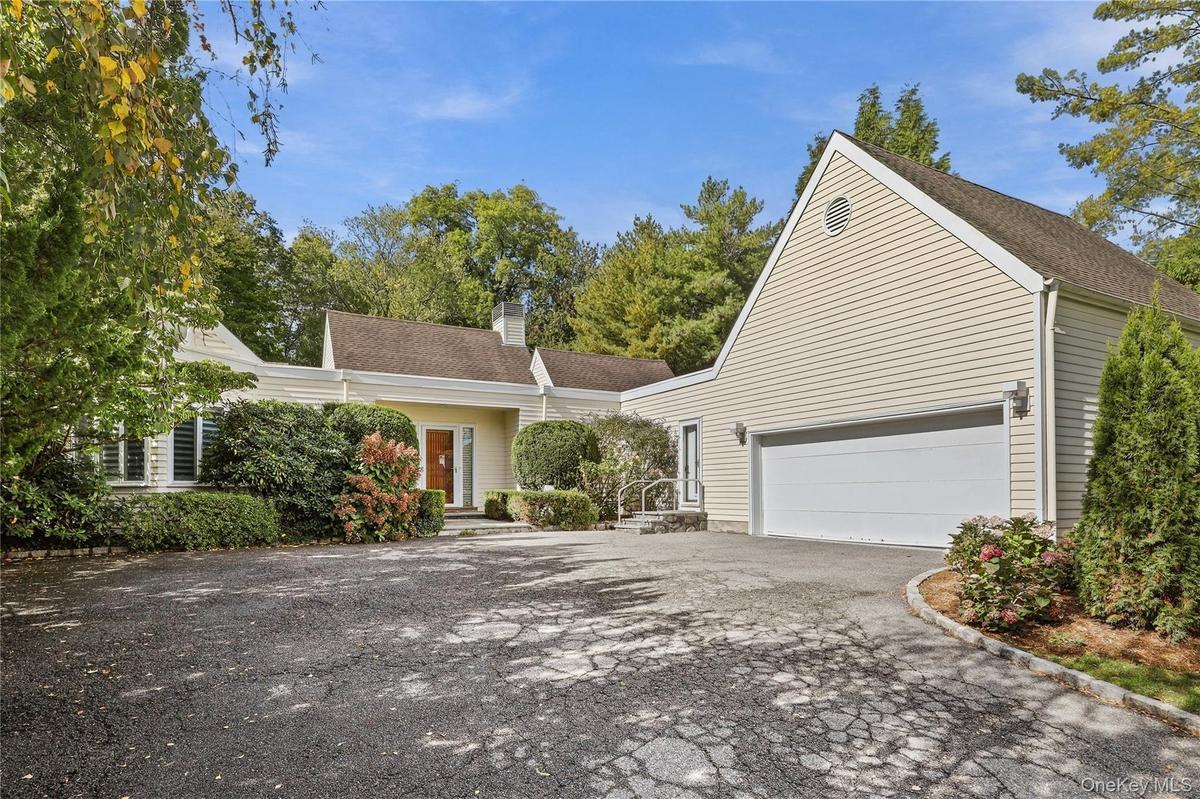Light-colored siding exterior with a multi-gabled roofline, an attached two-car garage, and a paved circular driveway