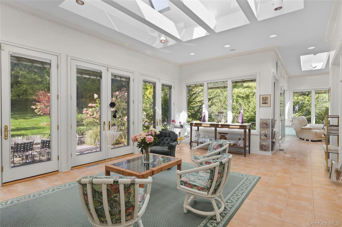 Sunroom featuring vaulted ceilings with skylights, extensive natural light through large windows, and multiple full-glass exterior doors with tile flo