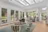 Sunroom featuring vaulted ceilings with skylights, extensive natural light through large windows, and multiple full-glass exterior doors with tile flo