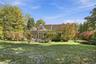 Expansive backyard featuring a lush lawn, mature landscaping, shingle-style roof.