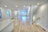 Open-concept interior featuring wood-finish flooring, recessed lighting, a stone-topped kitchen island, and a wooden handrail with vertical balusters