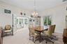 Dining area featuring crown molding, a central crystal chandelier, double glass-paneled doors, and large windows