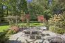 Flagstone patio featuring a natural stone retaining wall, mature trees, and established landscaping